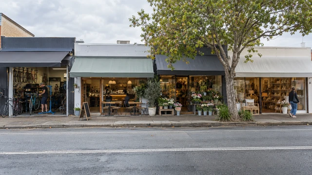 Several small businesses occupy neighbouring shopfronts along a suburban retail strip.