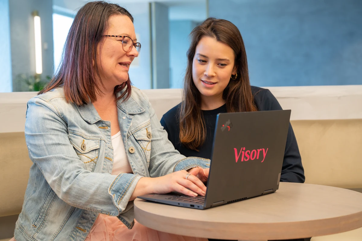 Two Visory colleagues review a laptop together.