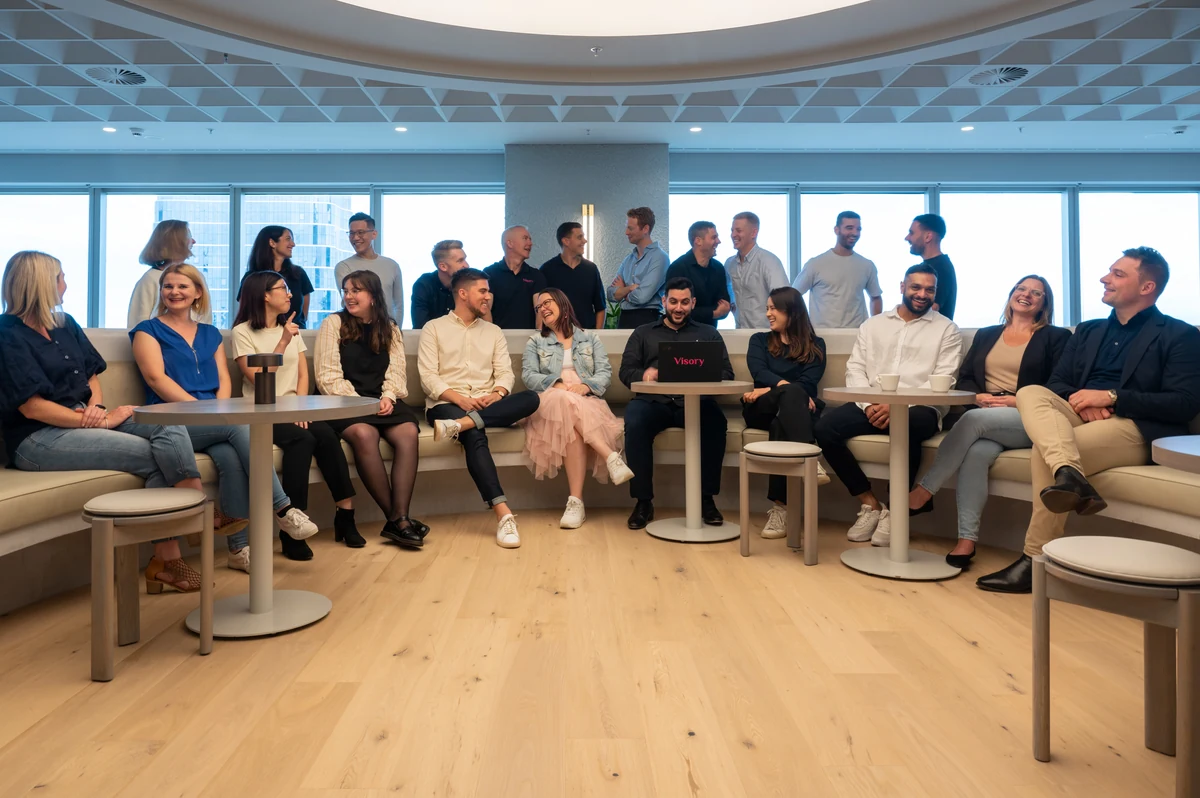 The Visory team gathers and talks together in an office lounge.