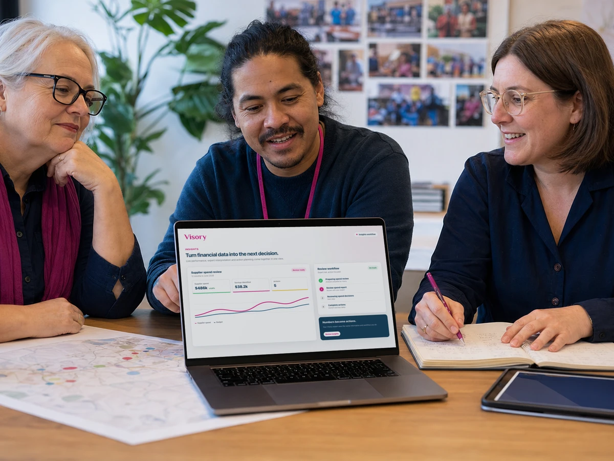 Three colleagues review financial information at a community office table.