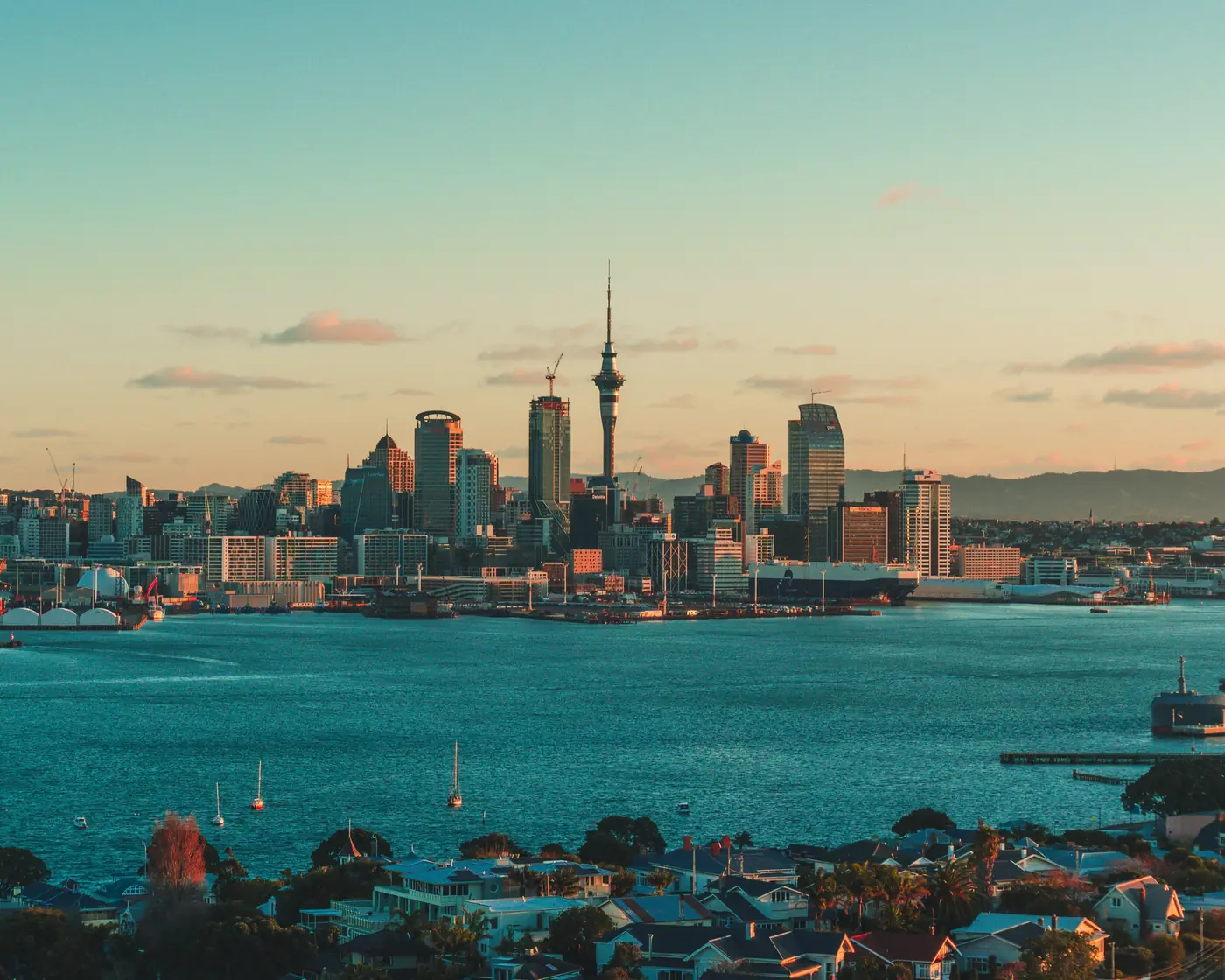 Auckland’s skyline and Sky Tower across the Waitematā Harbour in golden light, from Devonport.