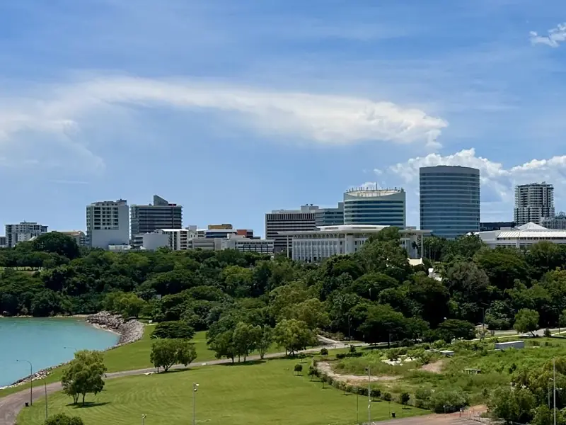 Darwin’s city buildings, including Parliament House, above tropical trees and the harbour.