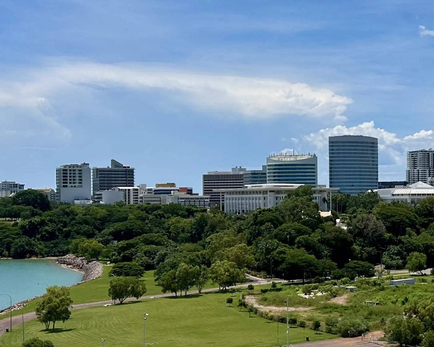 Darwin’s city buildings, including Parliament House, above tropical trees and the harbour.