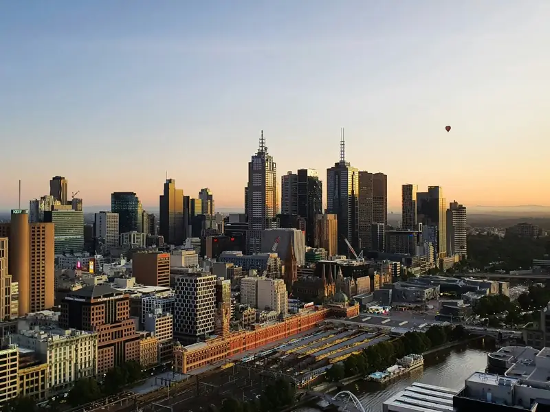 Melbourne’s city skyline at sunrise above Flinders Street Station and the Yarra River.
