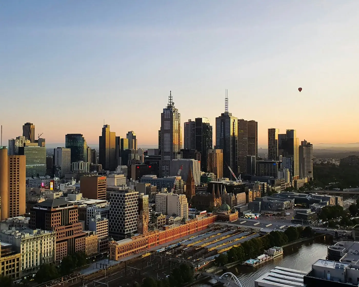Melbourne’s city skyline at sunrise above Flinders Street Station and the Yarra River.