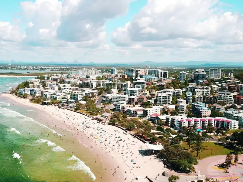 The Sunshine Coast from the air, with the beach, apartments and the Glass House Mountains on the horizon.
