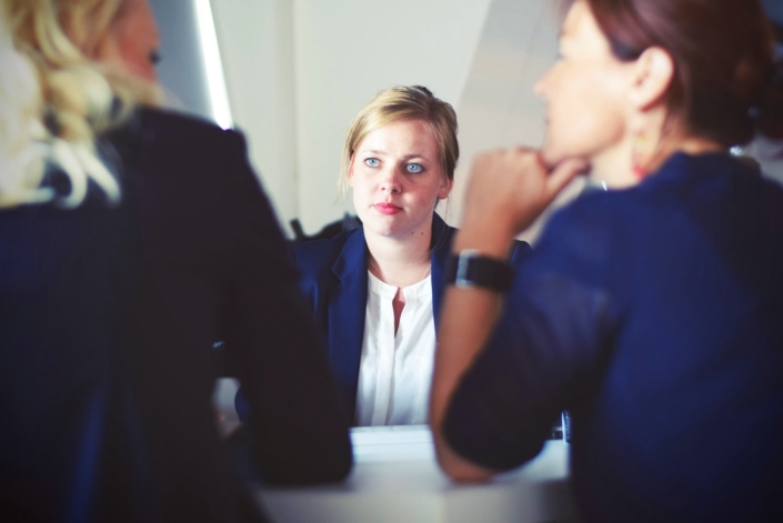 A woman faces two coworkers in the midst of a decision