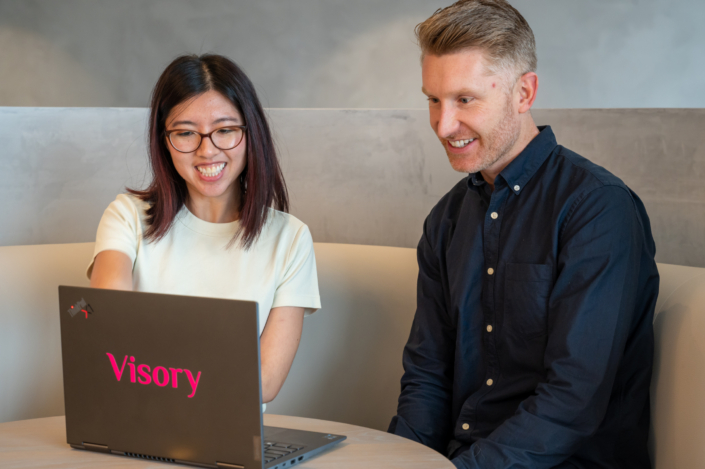 Two Visory team members reviewing work on a laptop